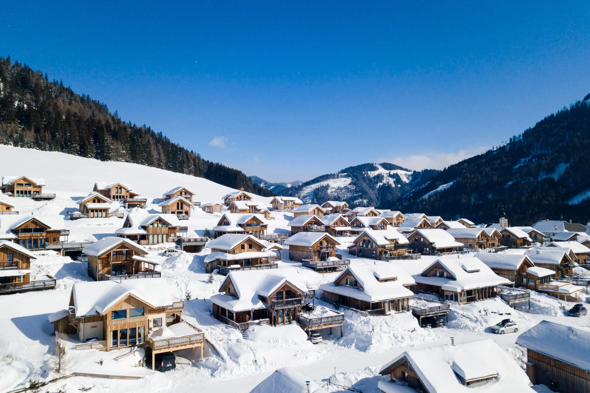 Luftaufnahme von Holzchalets im verschneiten Bergtal