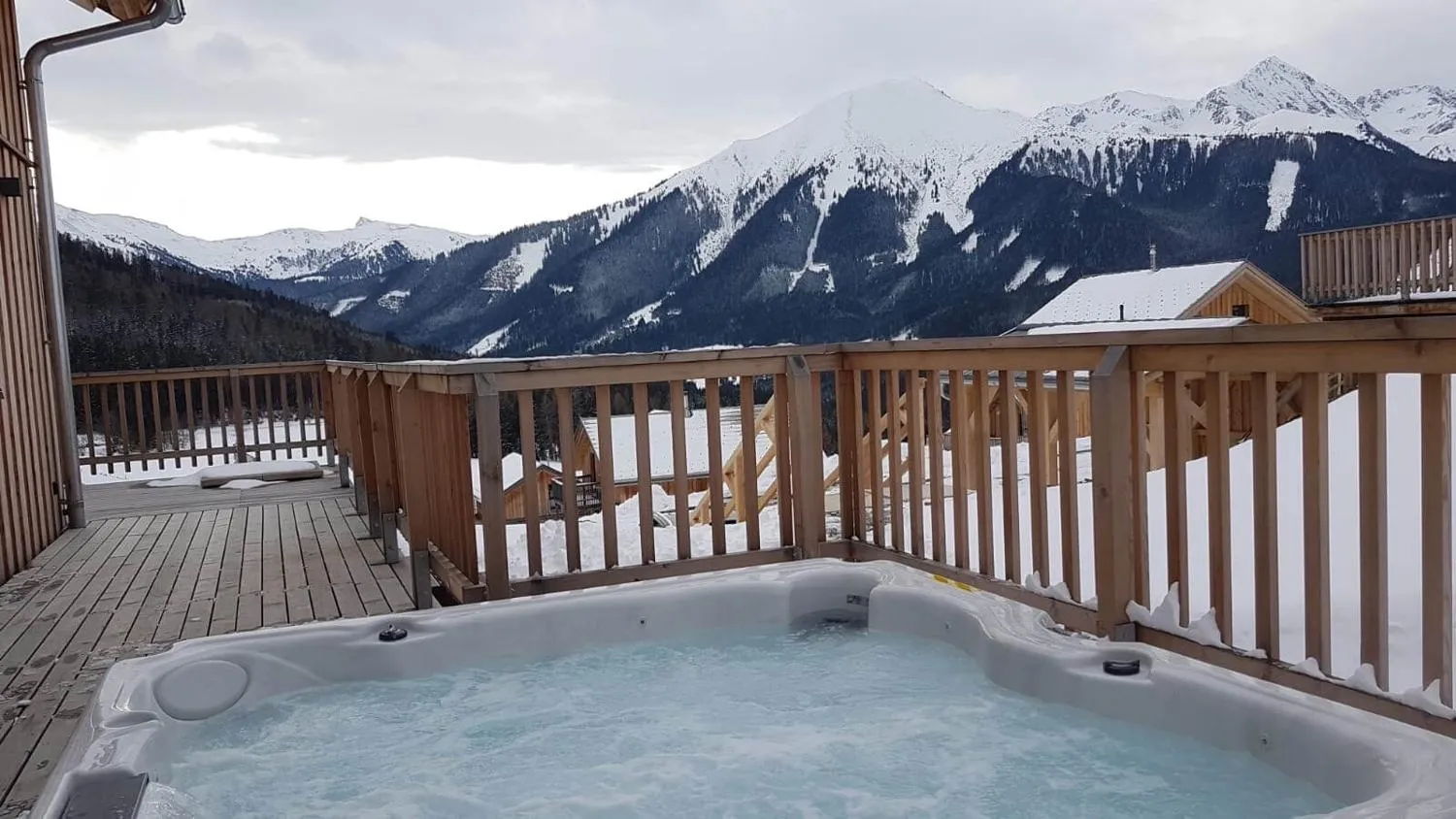 Whirlpool auf Balkon mit Bergpanorama und Skipisten im Winter