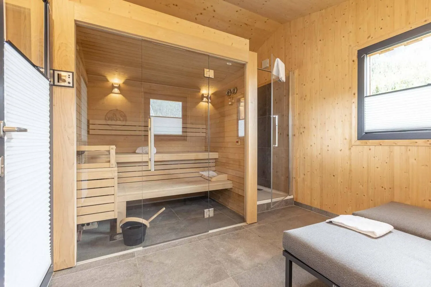 Moderne Saunakabine mit Glastüren in Holzinterieur und angrenzender Dusche