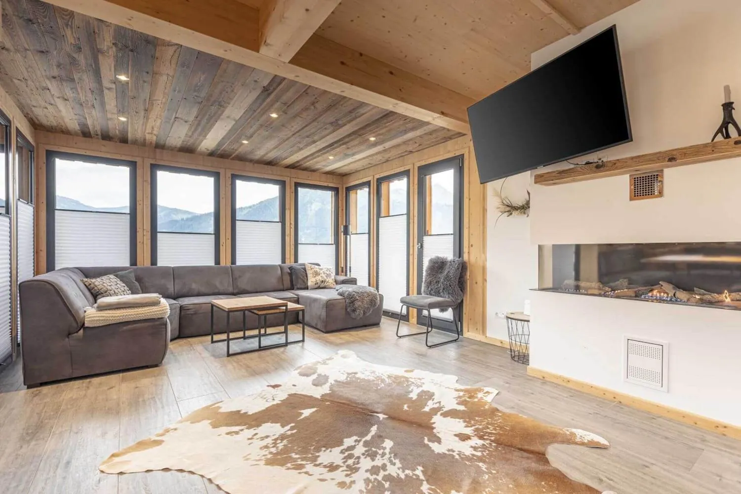 Wohnzimmer mit Ecksofa, modernem Kamin und weiter Bergaussicht