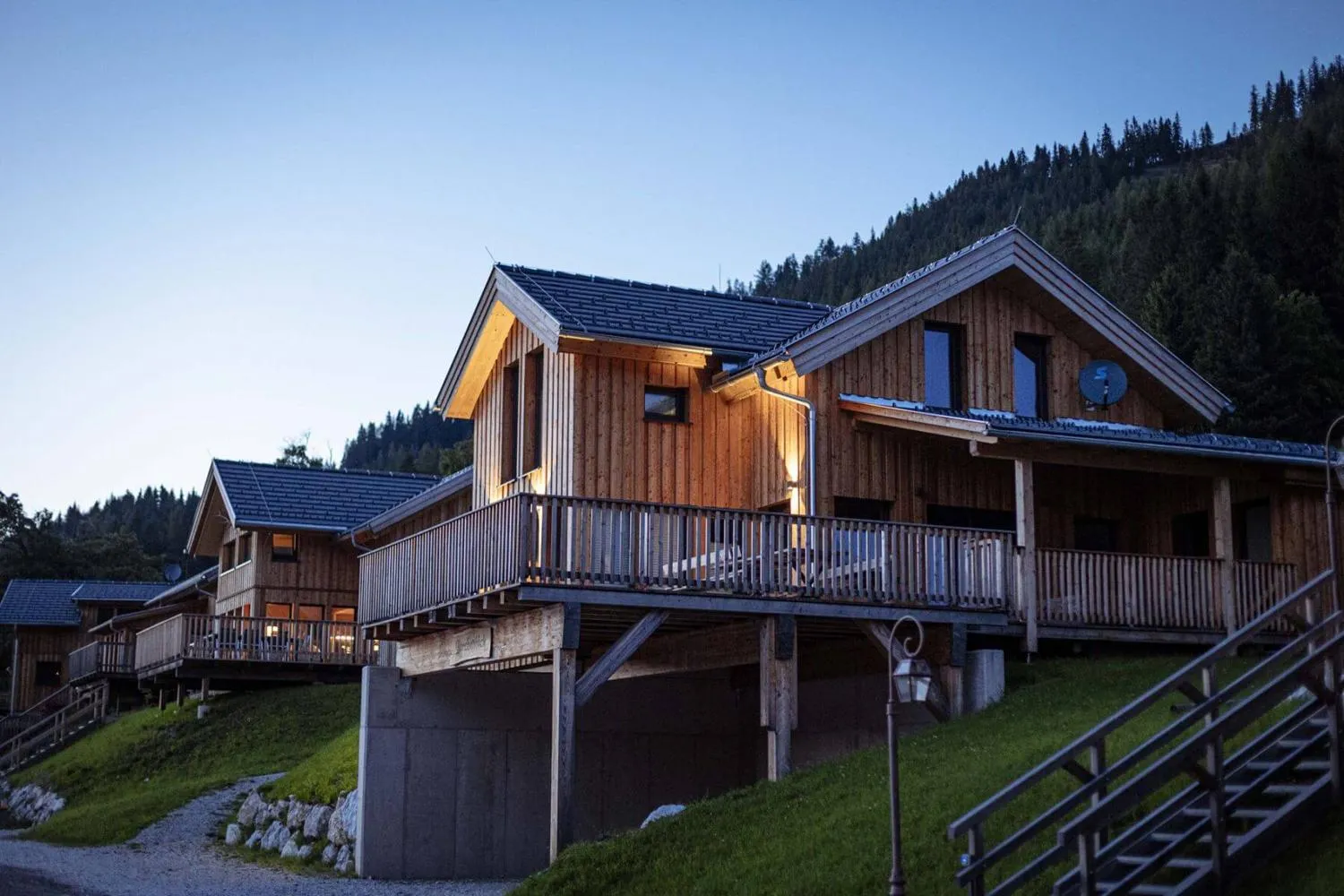 Moderne Holzchalets mit Balkonen in alpiner Waldlandschaft
