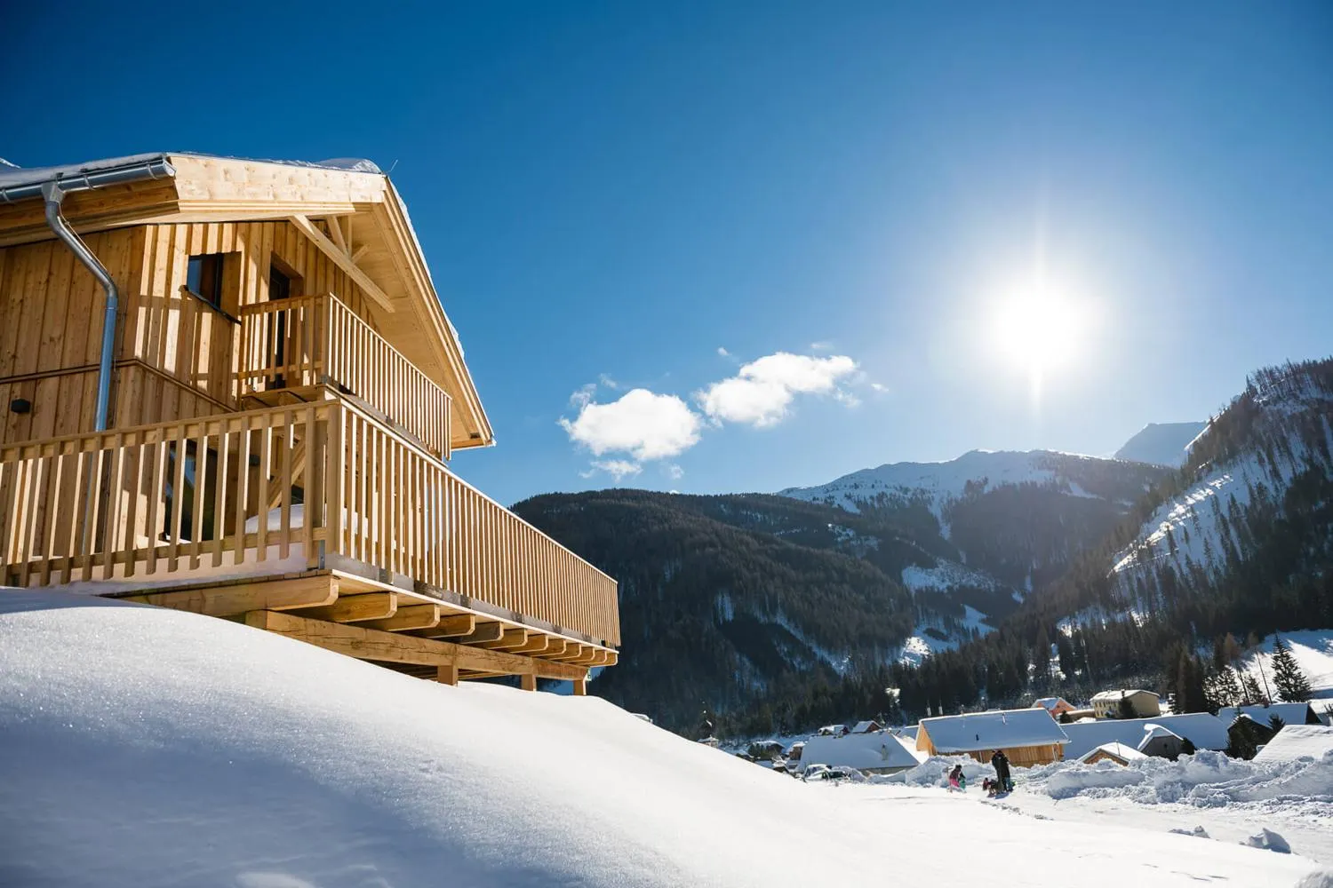 Holzchalet mit Balkon im Winter vor schneebedeckten Bergen