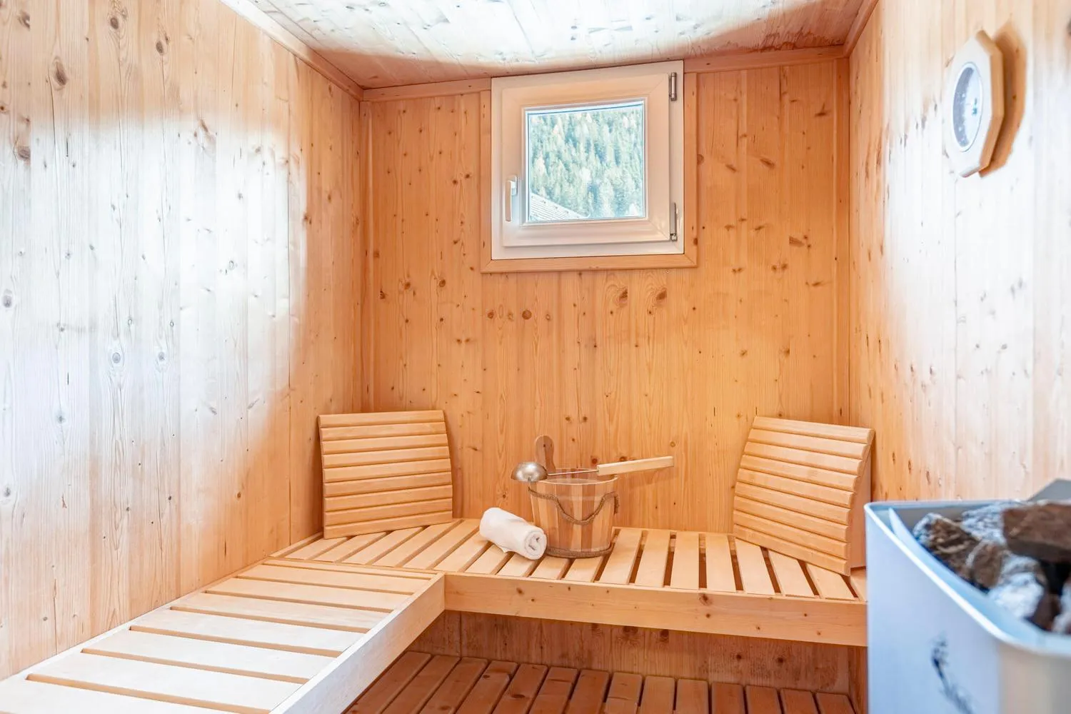 Holzsauna mit Sitzbänken und Fenster zum Tannenwald