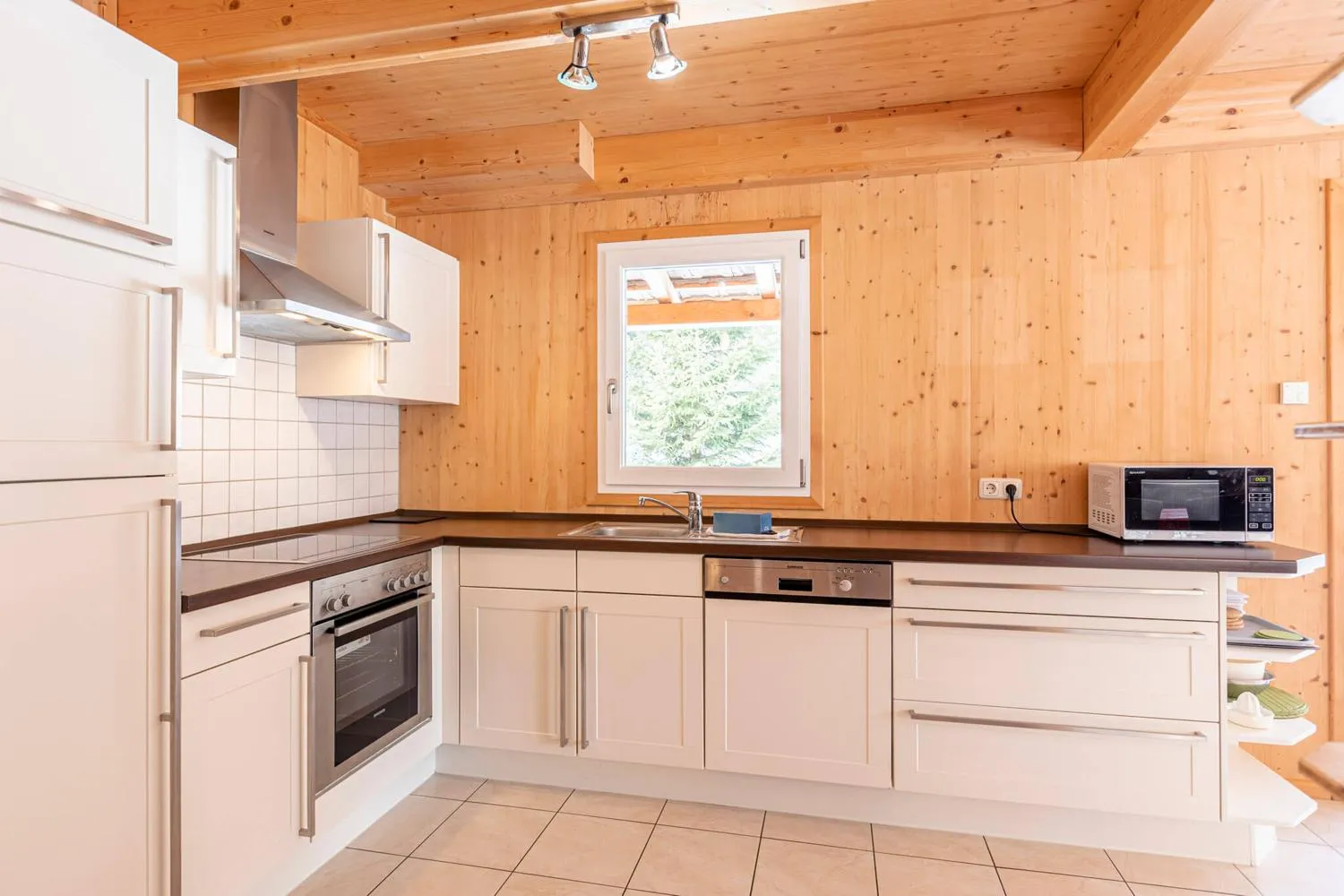 Holzküche mit Edelstahlgeräten, Fensterblick und Spülbecken