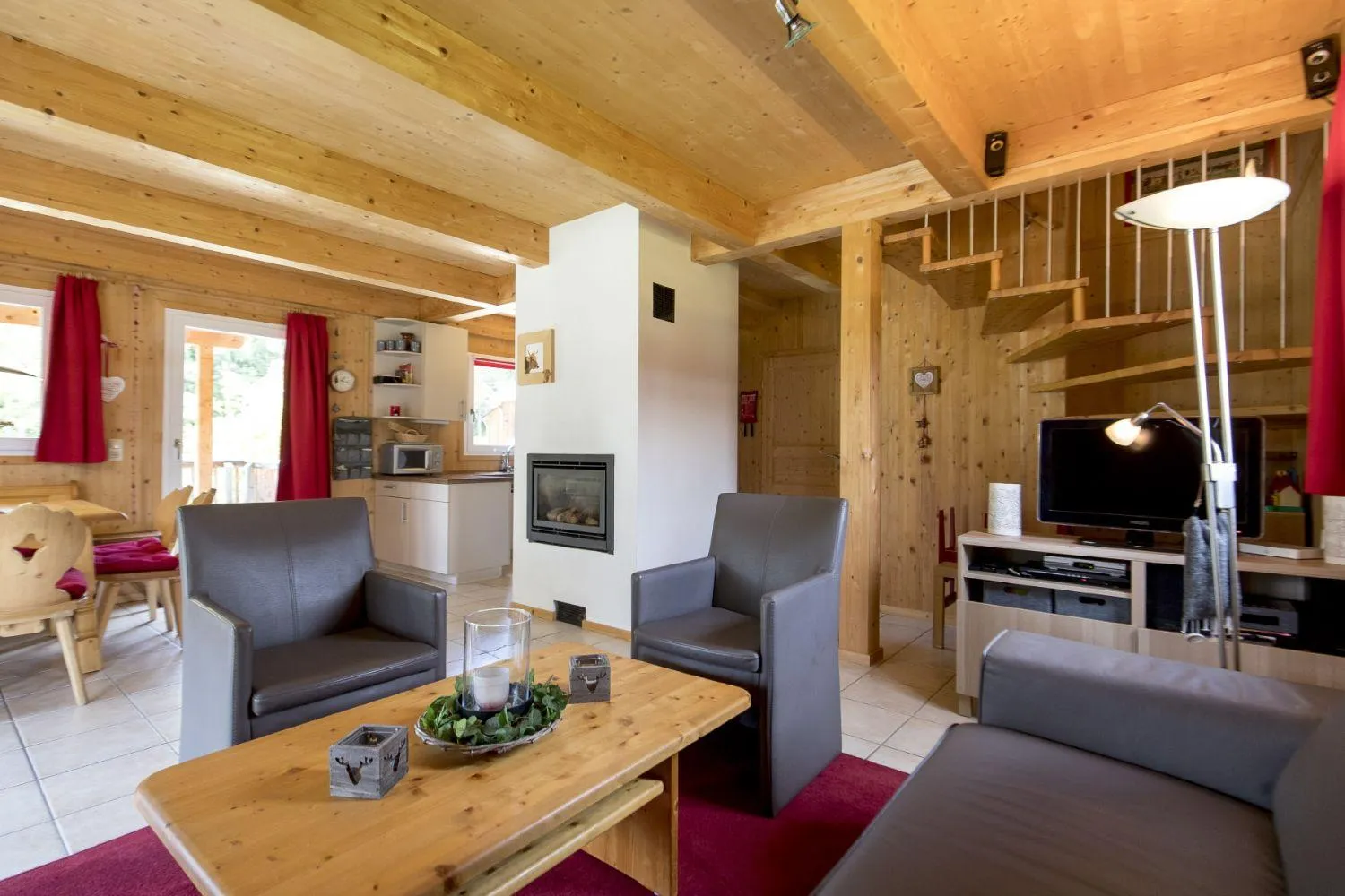 Geräumiges Wohnzimmer mit Holzdecke, Kamin und roten Vorhangakzenten