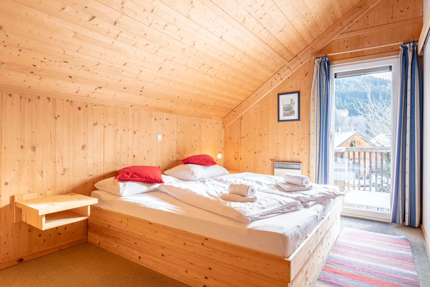 Schlafzimmer mit Doppelbett, roten Kissen und Balkonveranda