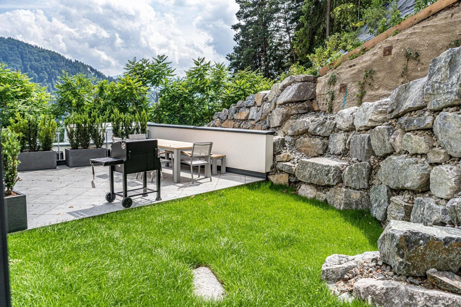 Garten mit Rasen, Grillstelle und Blick auf Berge und Tallandschaft