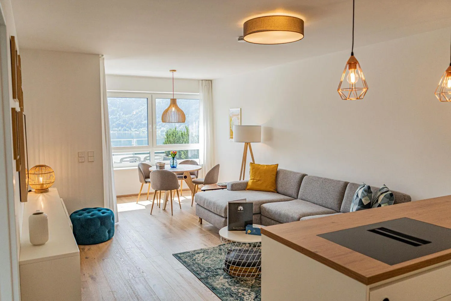 Wohnzimmer mit Sofa, Designleuchten und Ausblick auf See und Berge