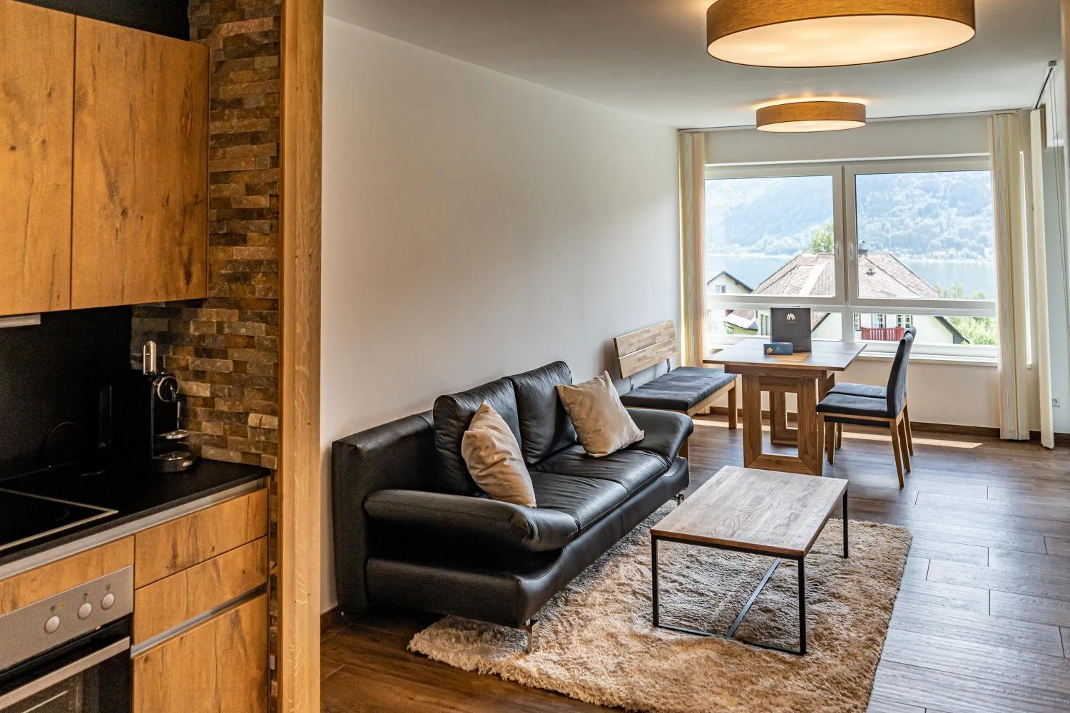 Wohnzimmer mit Ziegelkamin, Sofa und Panoramafenster zum See
