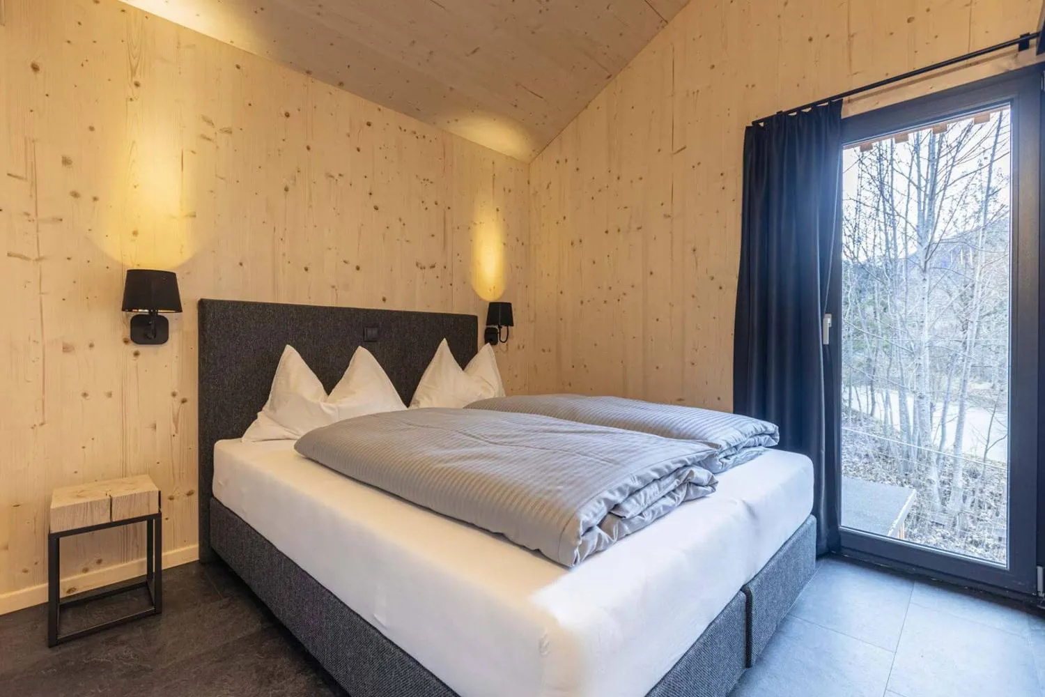 Geräumiges Schlafzimmer mit Holzverkleidung, Doppelbett und Waldblick