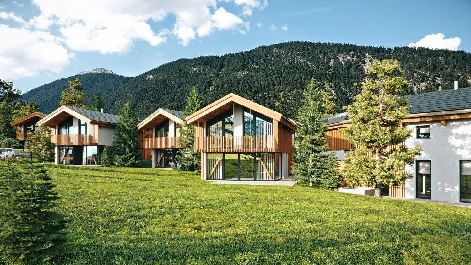 Moderne Alpenchalets mit großen Fenstern vor bewaldeten Bergketten