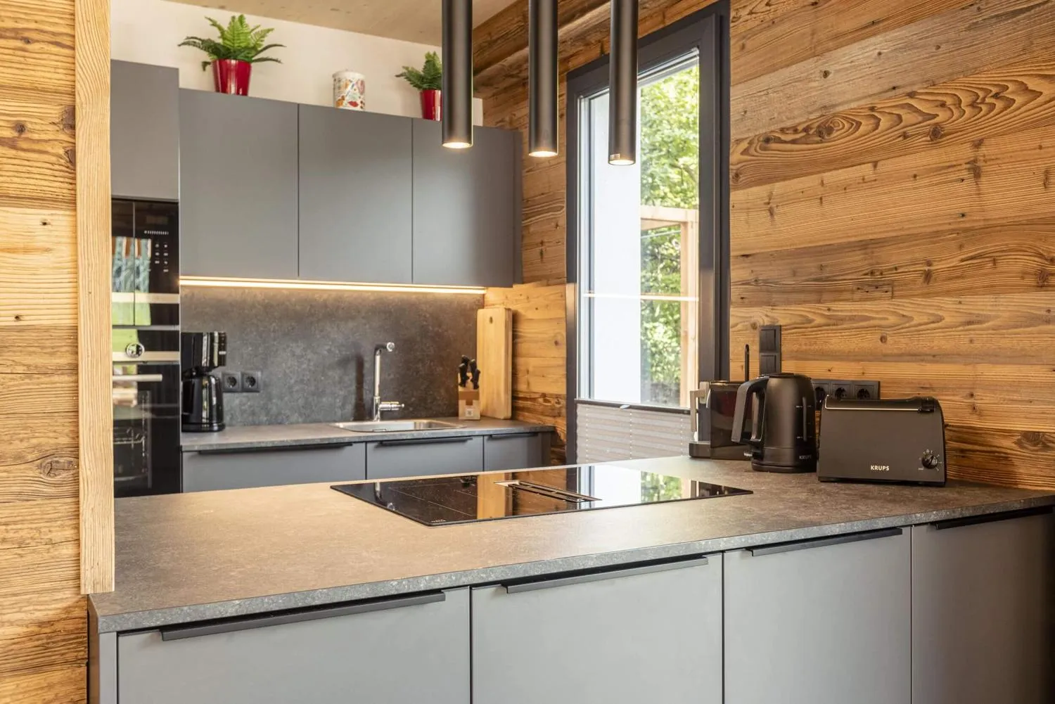 Moderne Küchenzeile mit Kücheninsel, Granitarbeitsplatte und Holzwänden