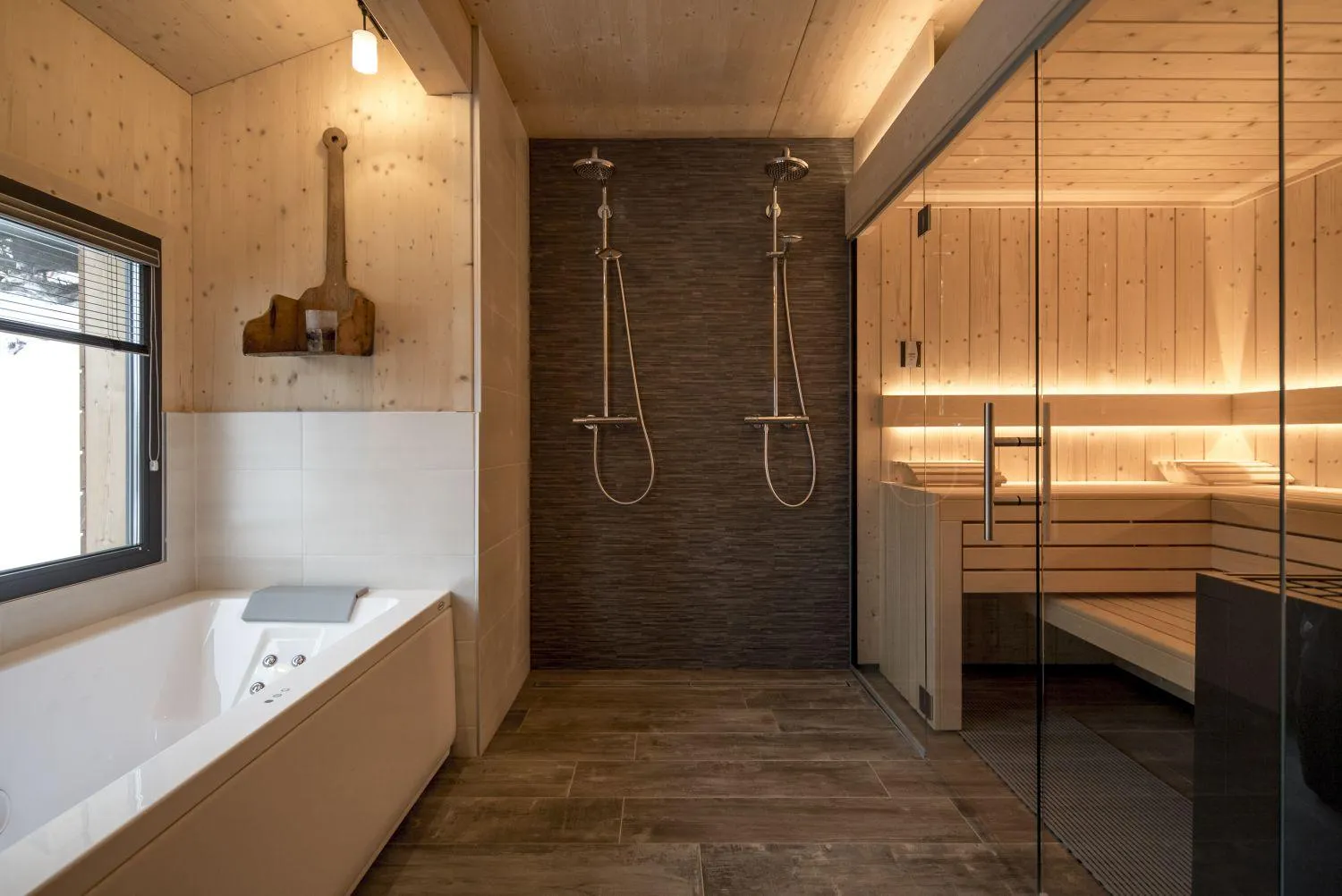 Badezimmer mit Whirlpoolwanne, Doppelregendusche und angrenzender Sauna