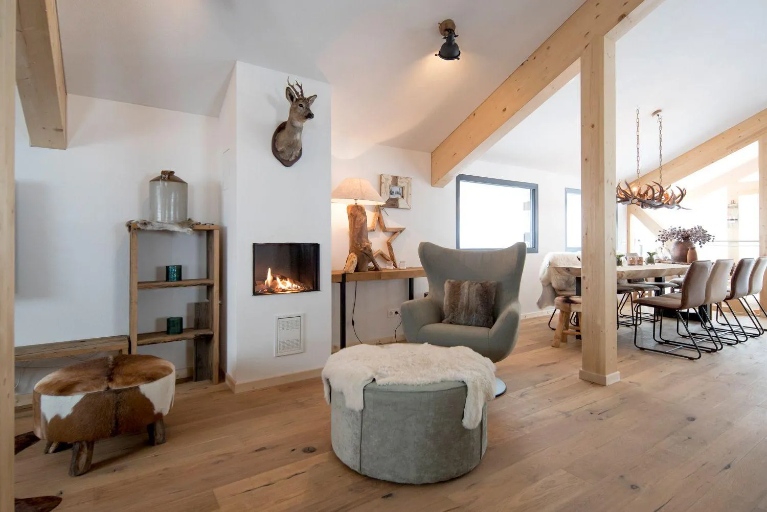 Modernes Wohnzimmer mit Kamin, grauem Sessel und Hirsch-Deko