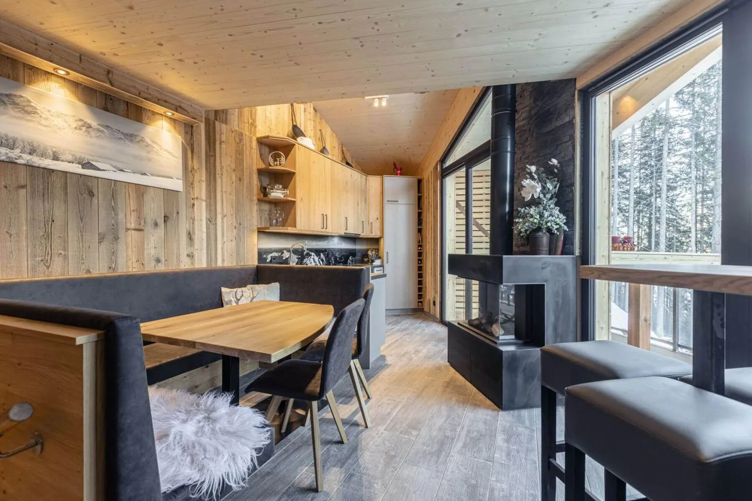 Moderne Essnische mit schwarzem Sofa, Holztisch und Waldblick