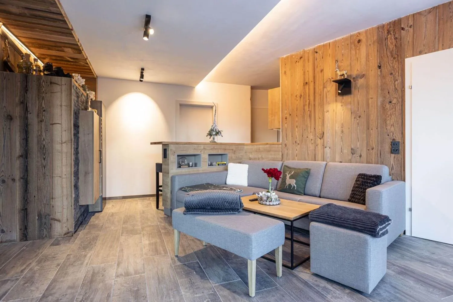 Helles Wohnzimmer mit grauem Sessel, Hirsch-Kissen und Kamin