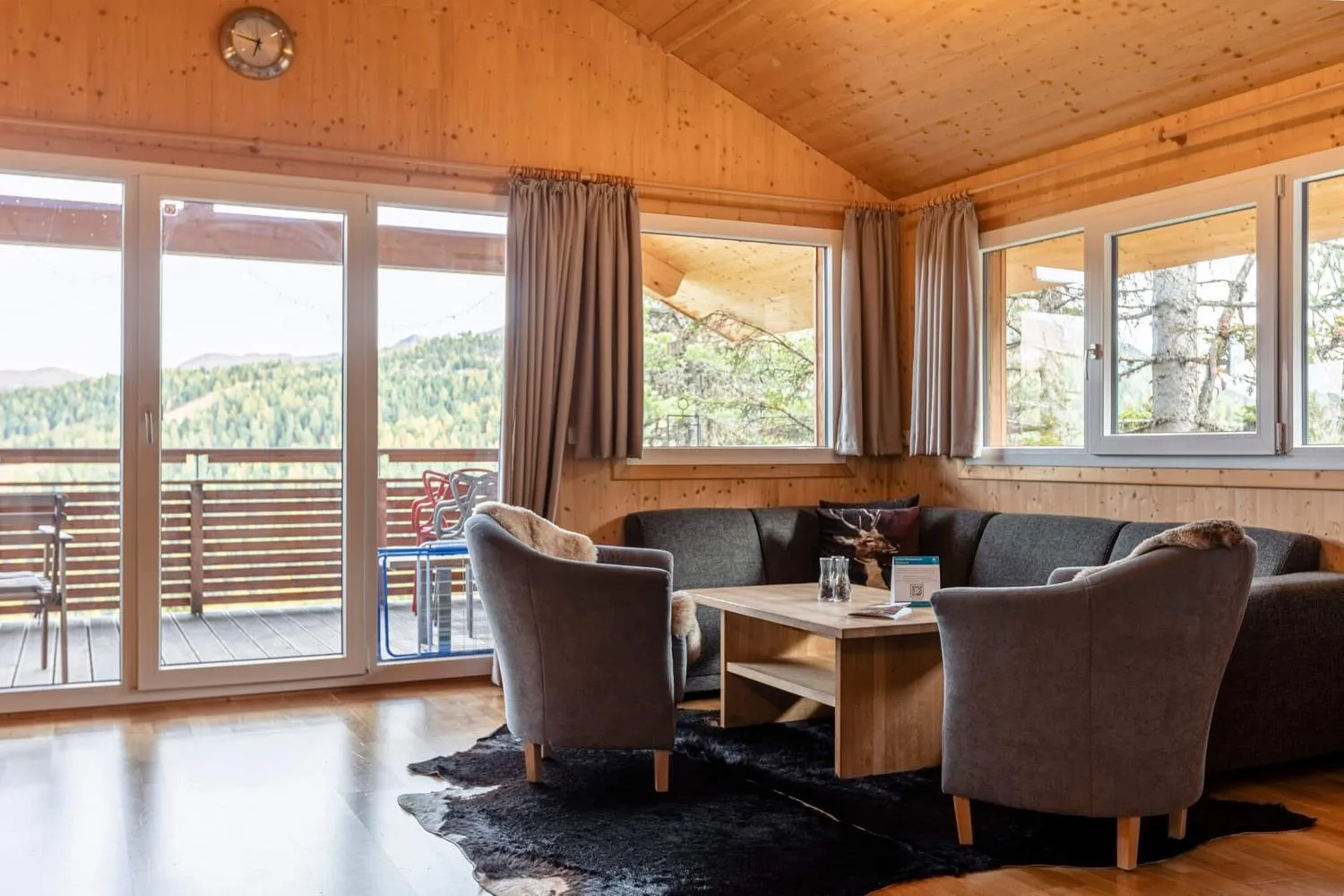 Großes Wohnzimmer mit Panoramafenstern zur Terrasse und gemütlichen Sesseln