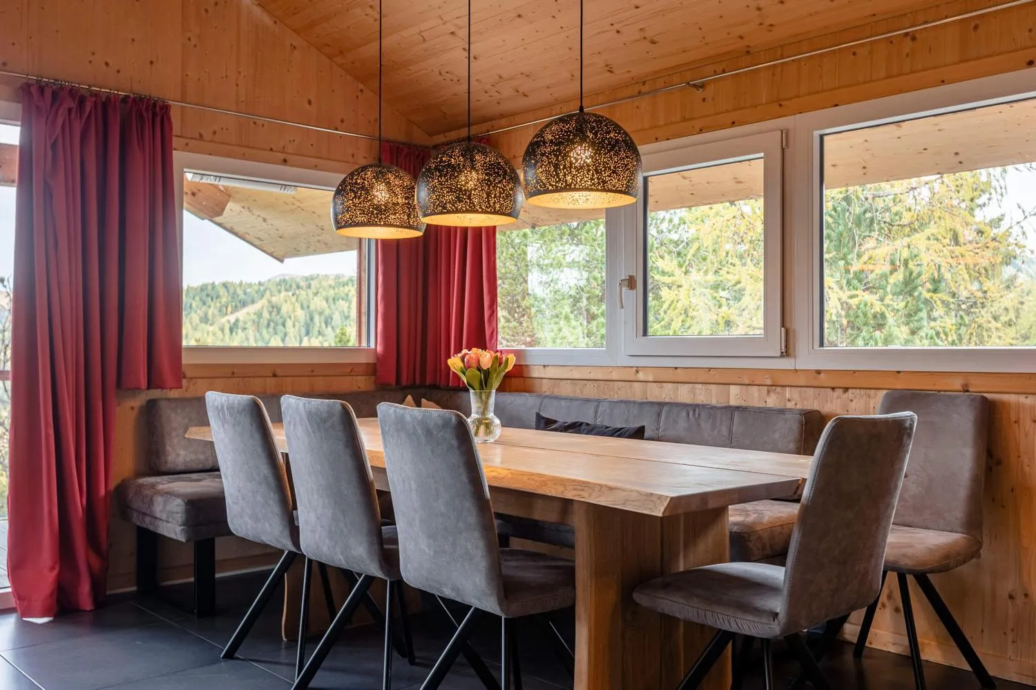 Modernes Esszimmer mit Holztisch, Waldblick und eleganten Hängelampen