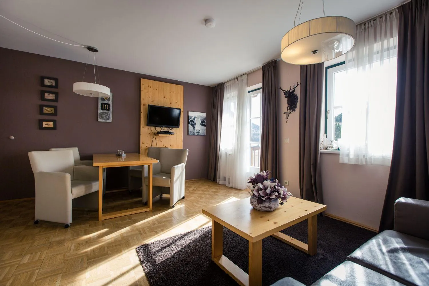 TV-Wohnzimmer mit Sessel, Kamin und Fensterblick in eleganter Waldthematik