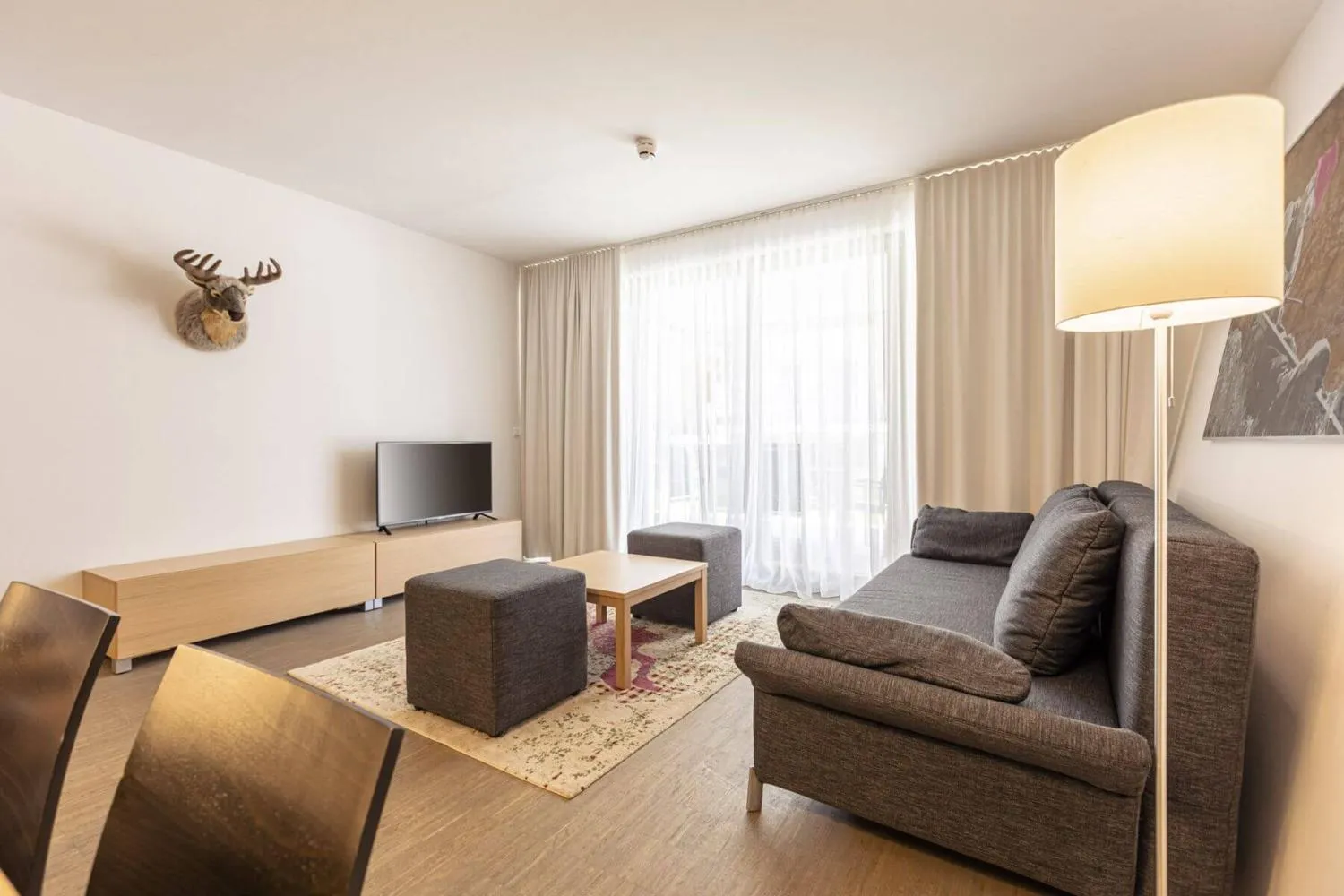 Wohnzimmer mit grauem Sofa, Hirschkopf an der Wand und Sideboard