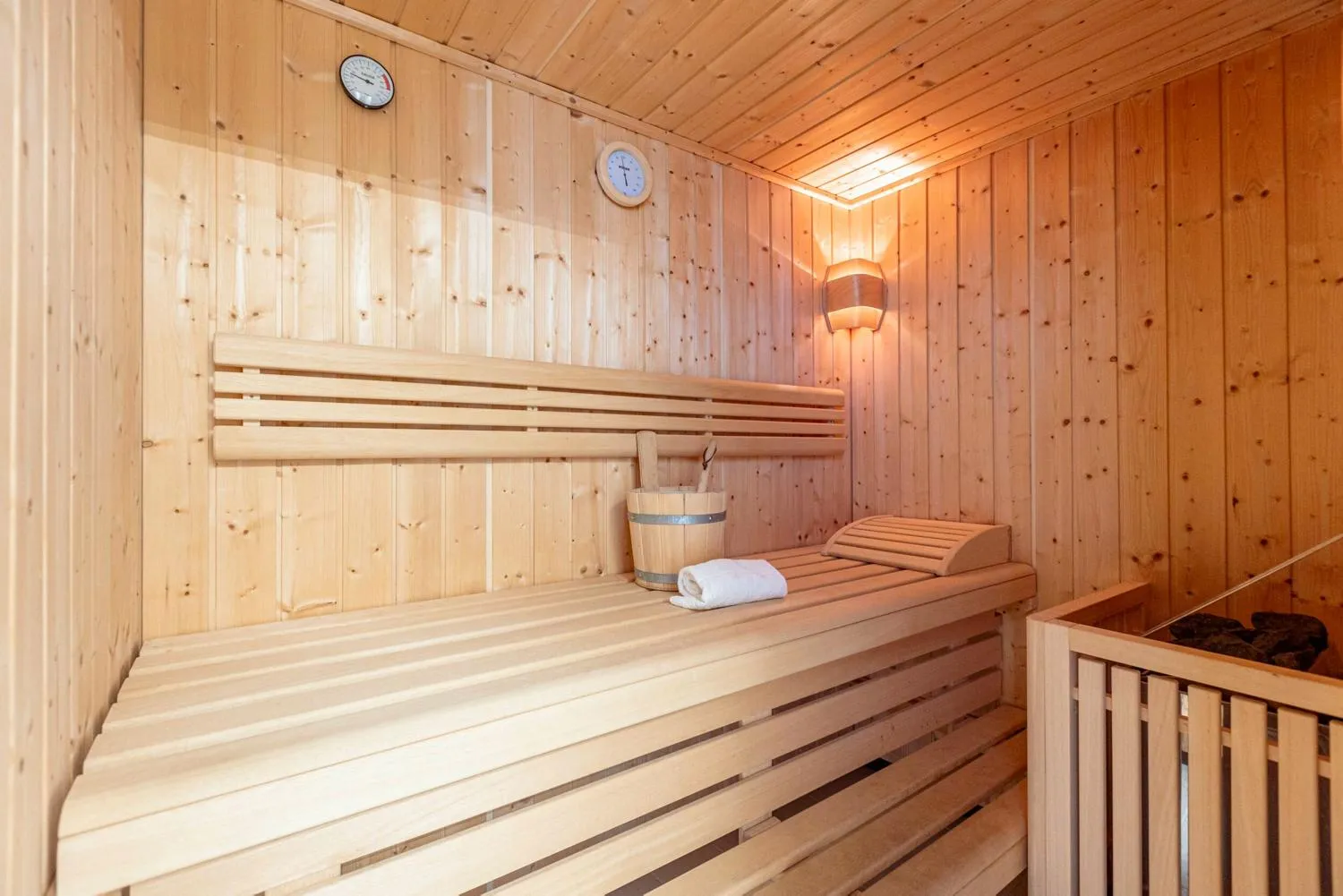 Holzsauna mit traditionellen Bänken, Kübel und weißem Handtuch
