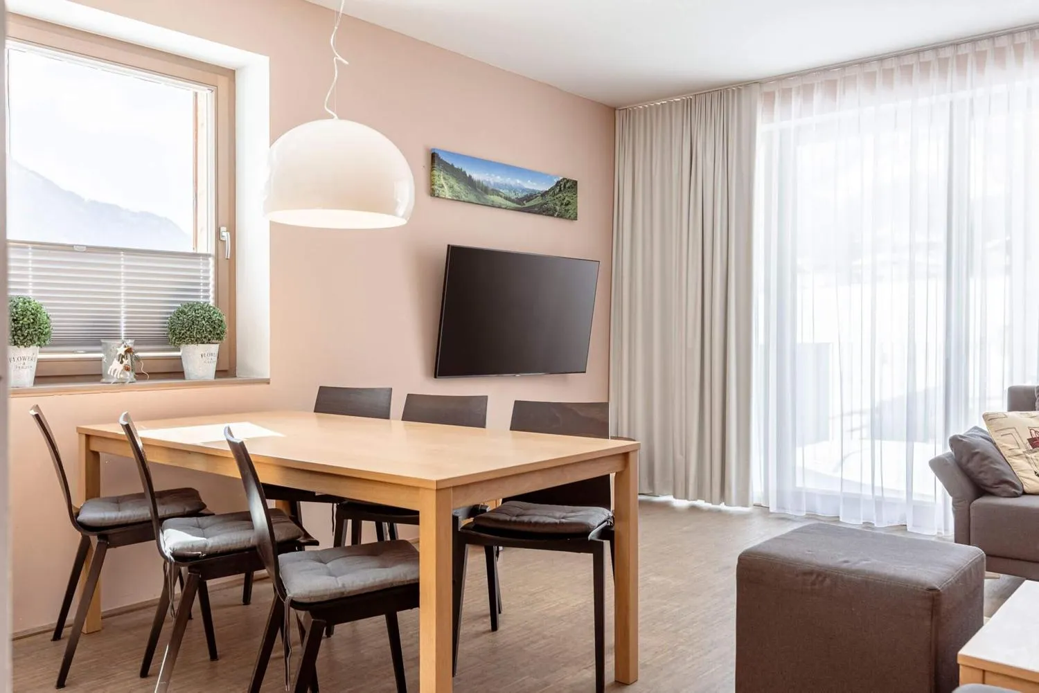 Essbereich mit Holztisch, Sesseln und Bergpanorama im Fenster