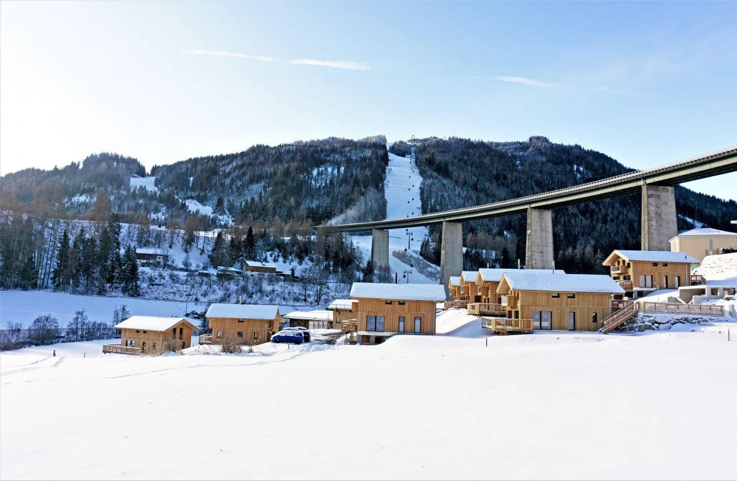 Winterszenerie mit schneebedeckten Chalets und Skipiste in Alpenlandschaft