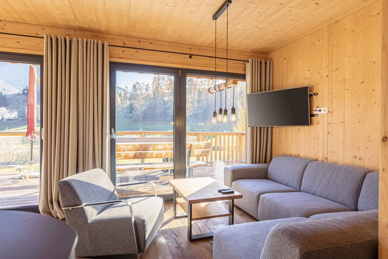 Wohnzimmer mit Sofa und Bergblick durch große Terrassenfenster