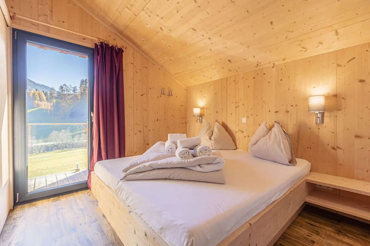Schlafzimmer in heller Holzverkleidung mit Bergblick und großem Bett