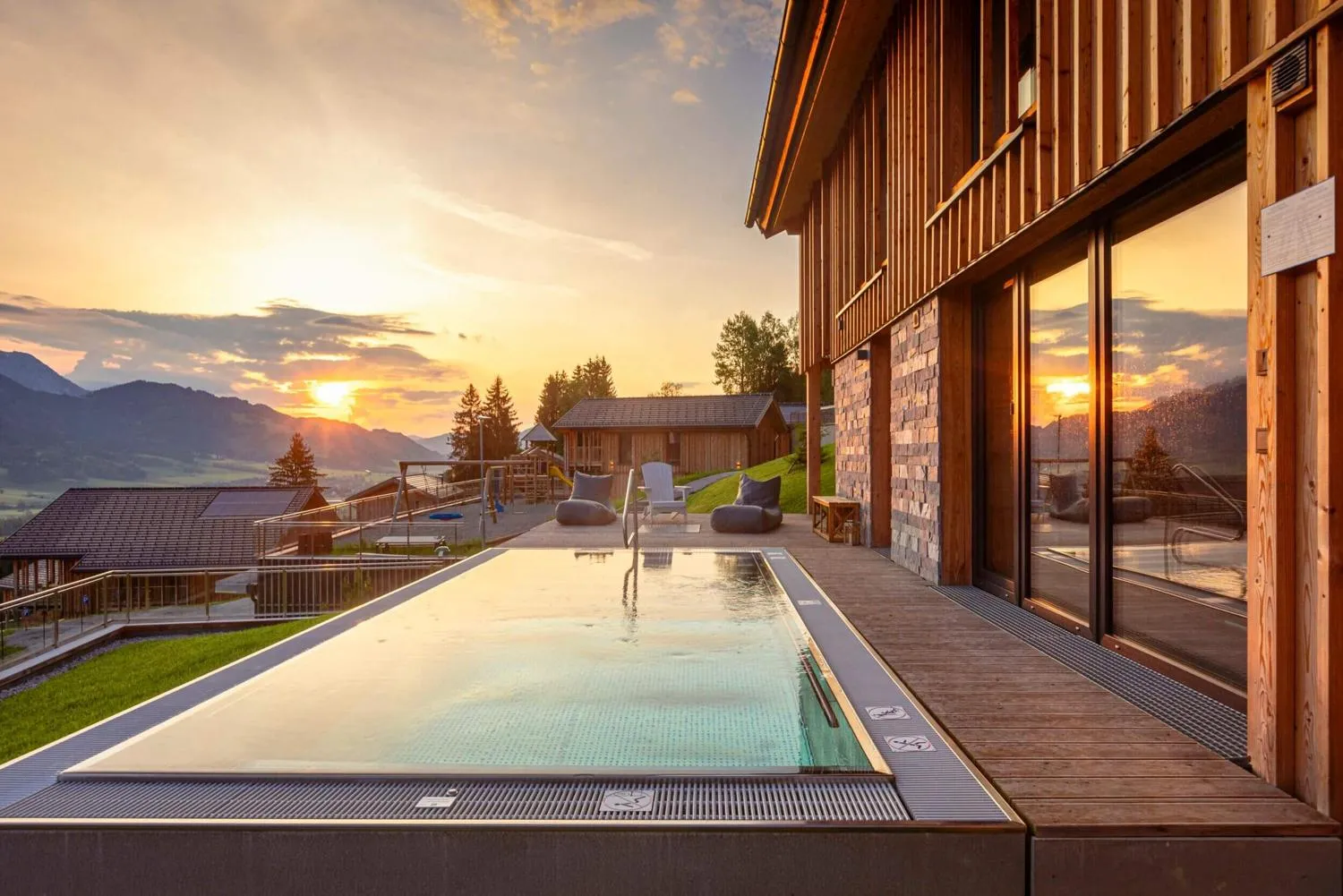 Pool bei Sonnenuntergang mit Bergpanorama und Holzgebäude