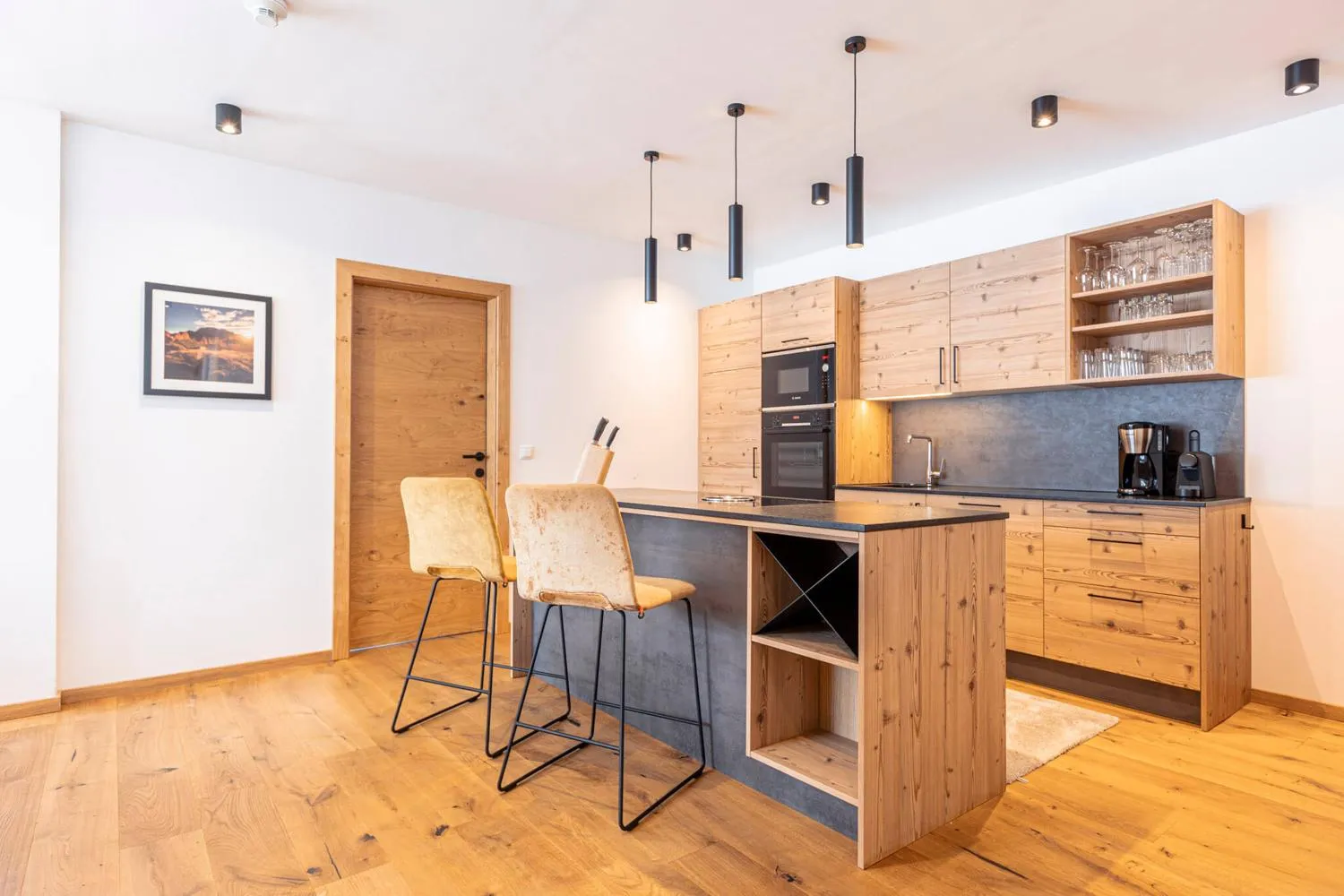 Moderne Küche mit Holzschränken, schwarzer Arbeitsplatte und Barhocker