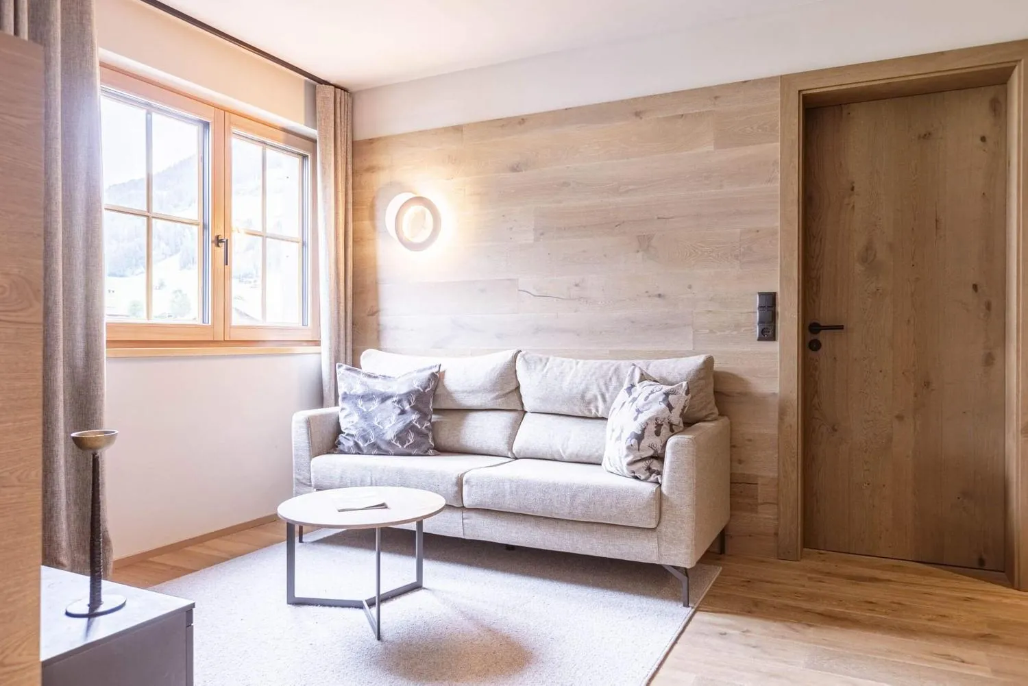 Aufenthaltsbereich mit Holzwandpaneel, breitem Sofa und Bergfenster