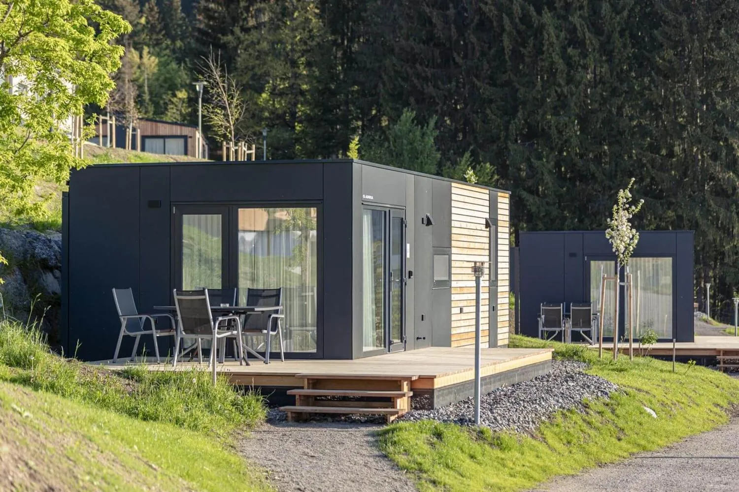 Zwei schwarze moderne Chalets mit Veranda und Waldumgebung