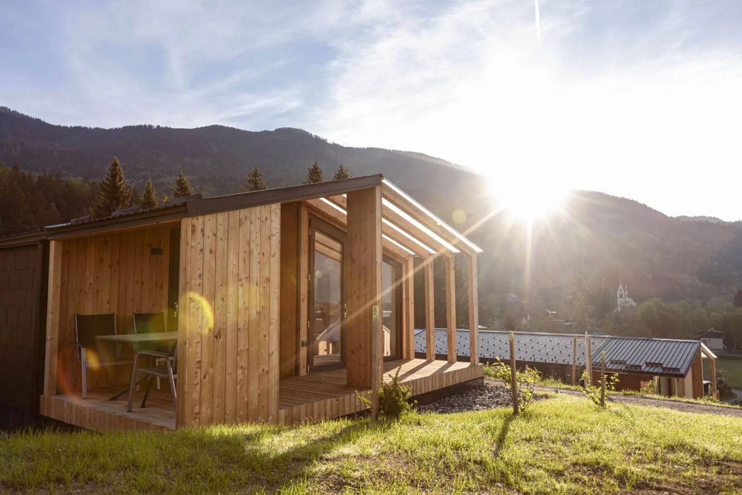 Holz-Glamping-Pod bei Sonnenaufgang mit Pergola-Veranda im Tal