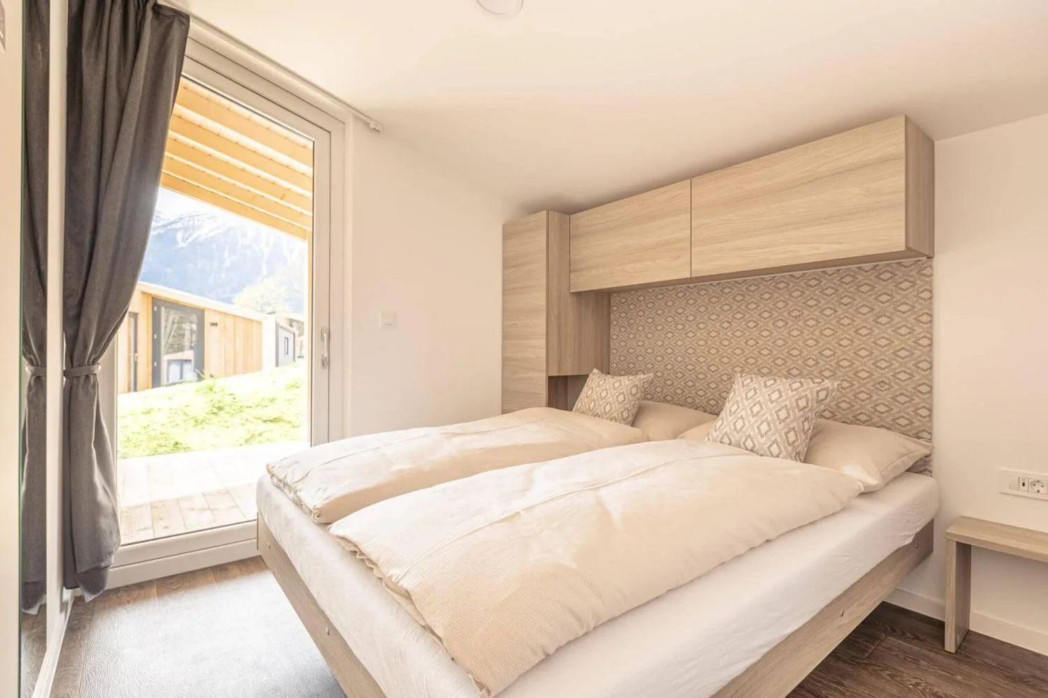 Helles Schlafzimmer mit Doppelbett und großem Bergfenster