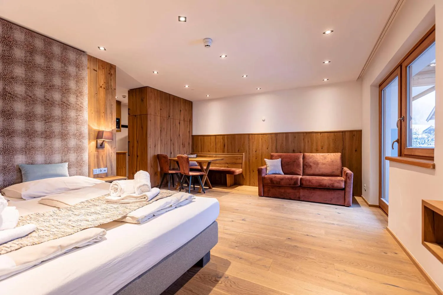 Geräumiges Schlafzimmer mit Holzwand und Wohnbereich