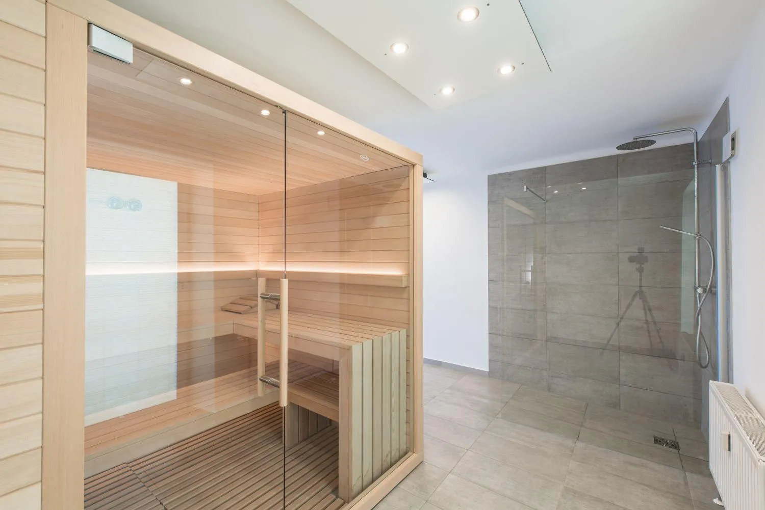 Wellness-Bereich mit Holzsauna und großer Glasdusche mit Fensterblick