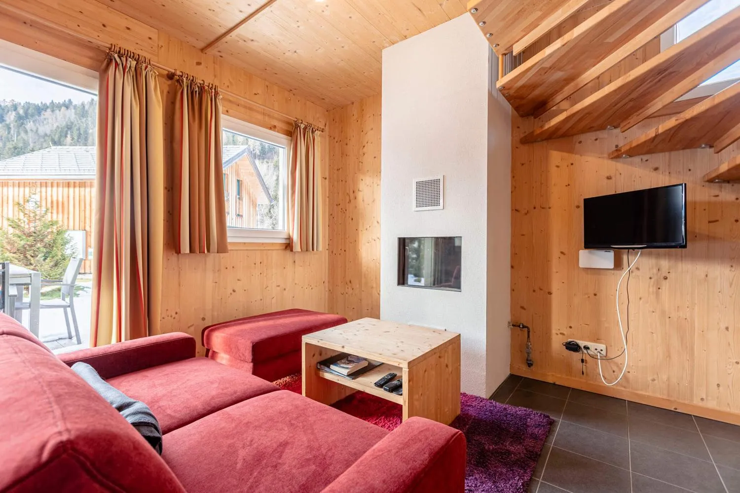 Modernes Schlafzimmer mit rotem Bett, Fernseher und Holzwänden