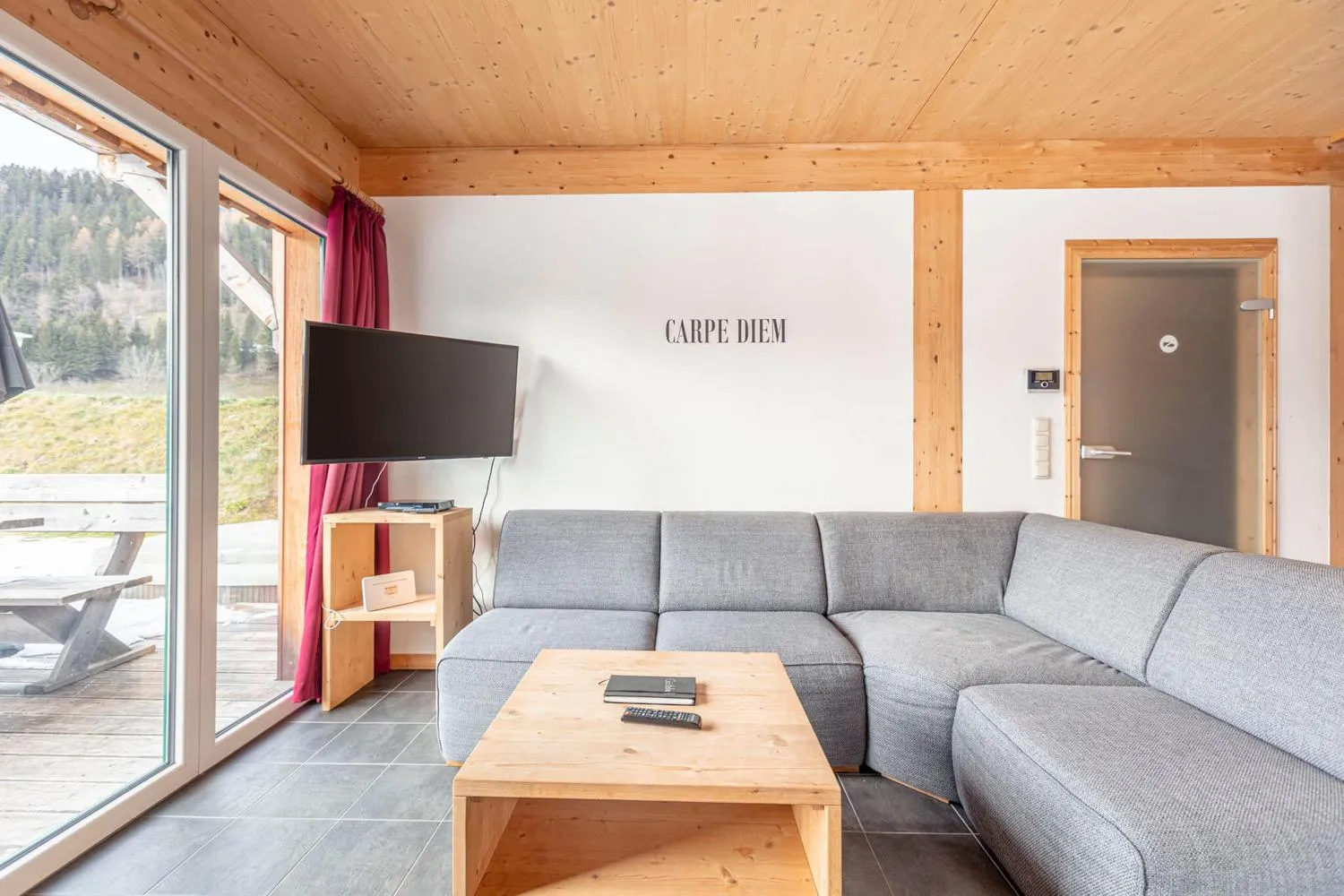 Wohnzimmer mit großem grauem Sofa, Fernseher und Bergsicht
