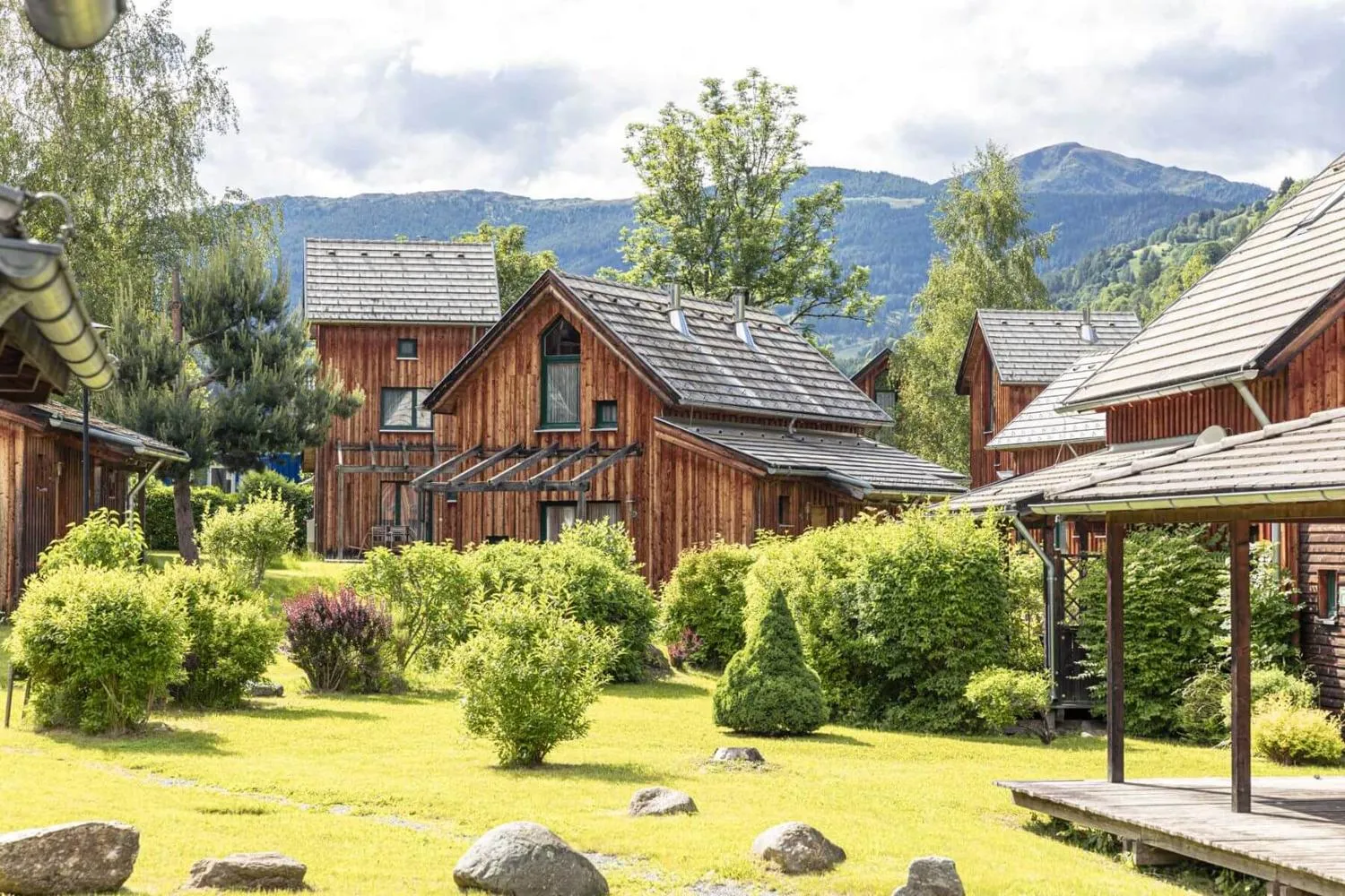 Ferienpark-Übersicht mit Holzhütten, Grün und Bergen