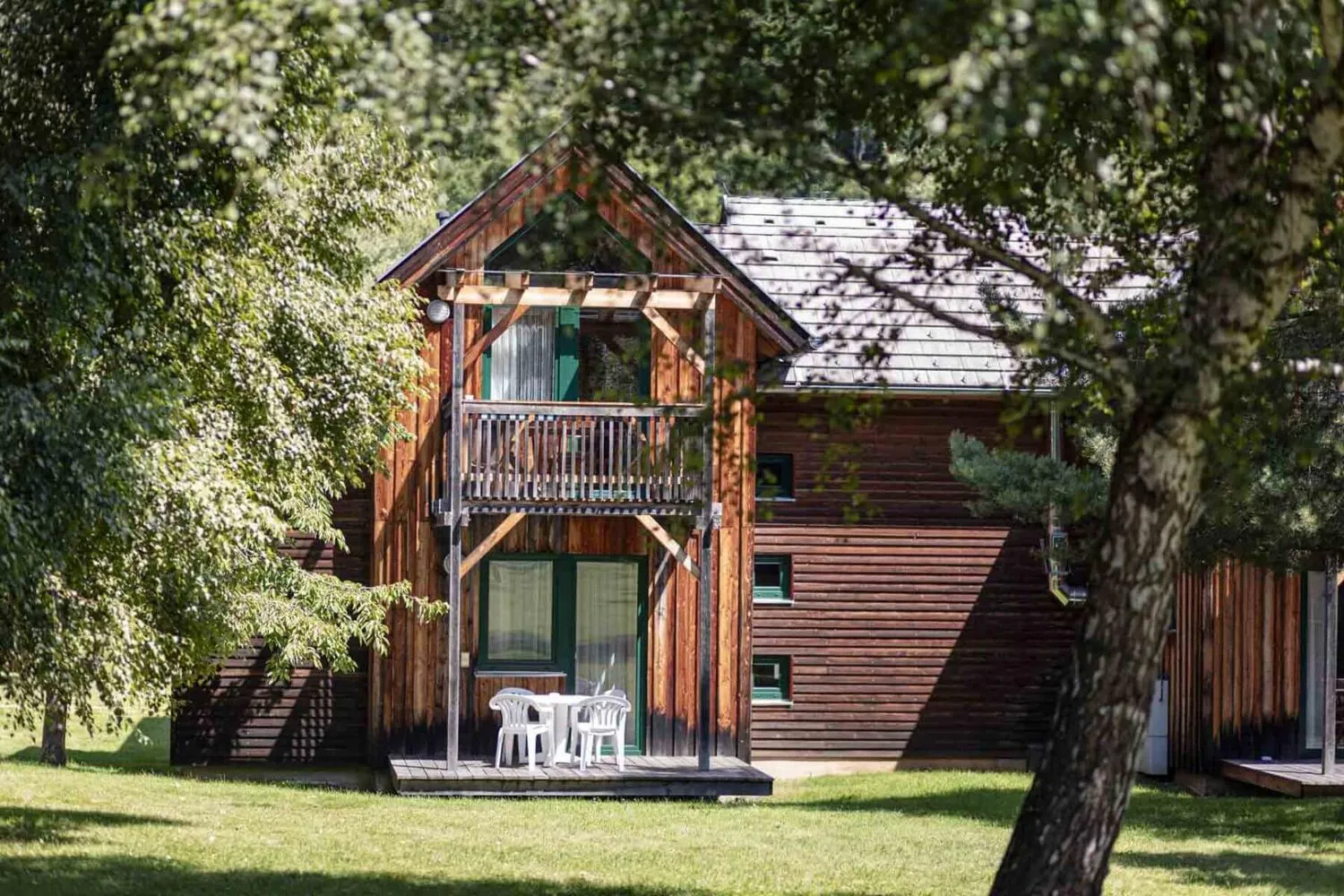 Holzferienhütte mit Balkon umgeben von Bäumen