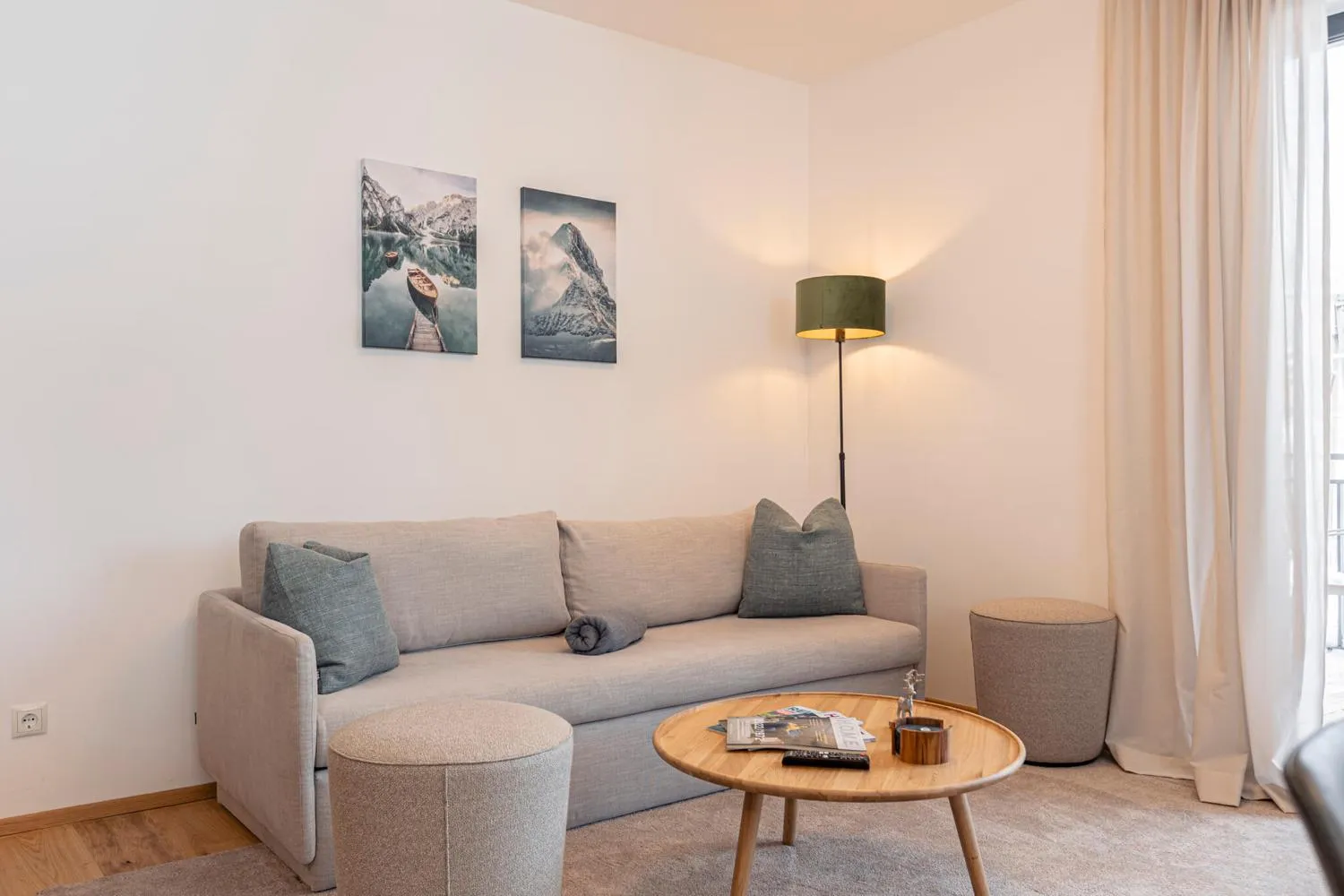 Wohnzimmer mit grauem Sofa und Berglandschaftsfotos