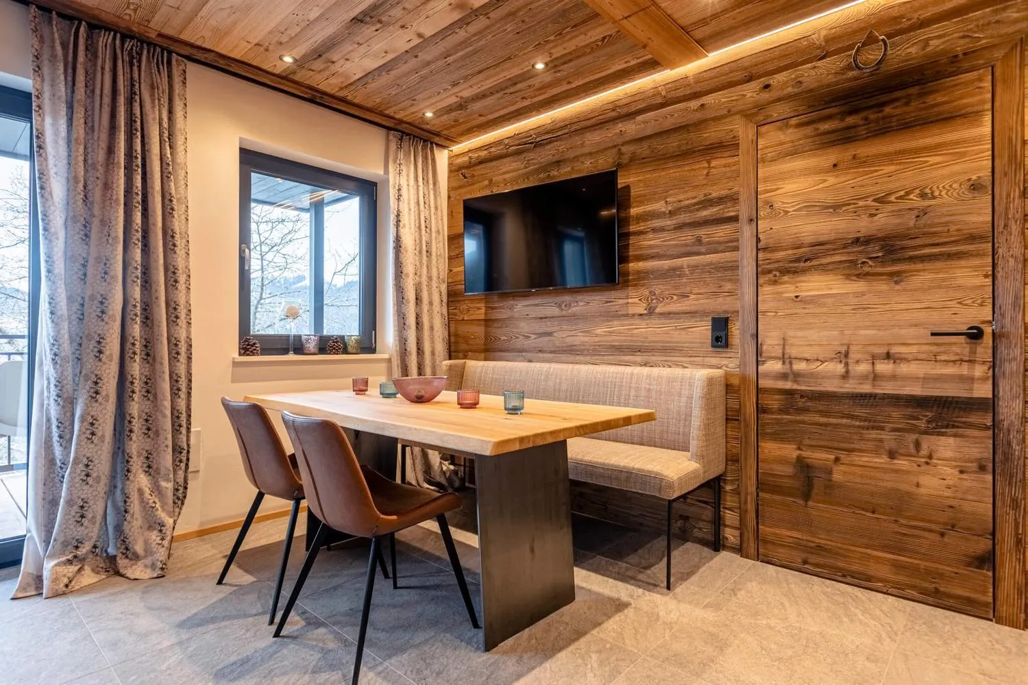 Speiseraum mit Holzdecke und Fensterblick auf Schneefeld