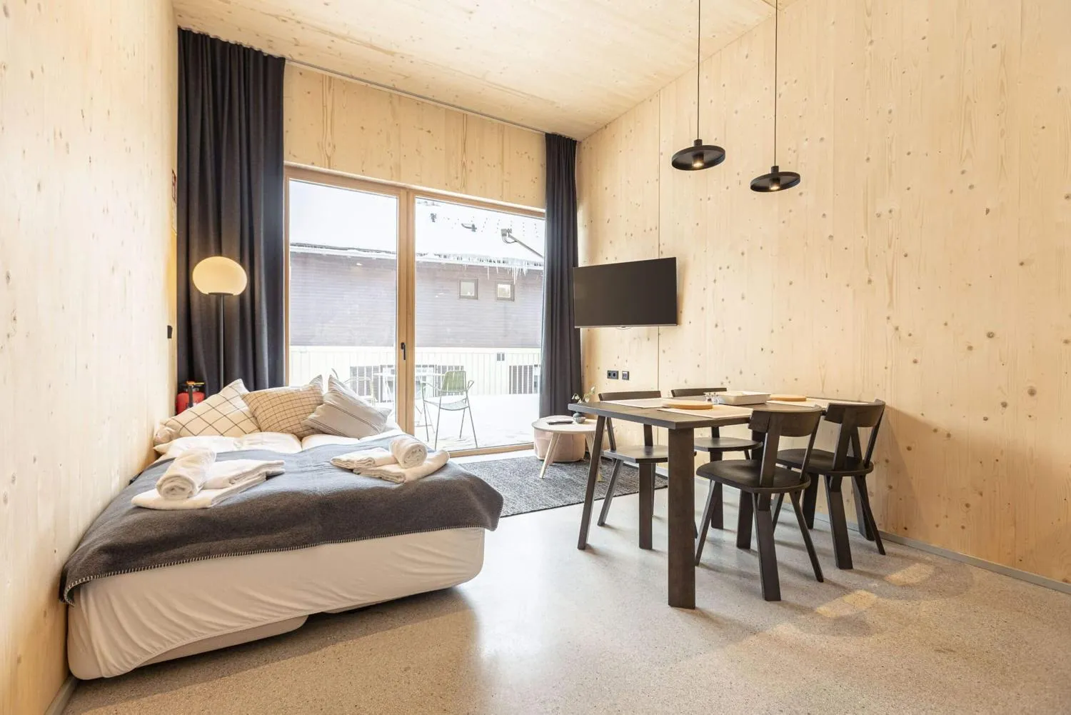 Schlafzimmer mit Holzwänden, Fensterblick und integriertem Arbeitsbereich