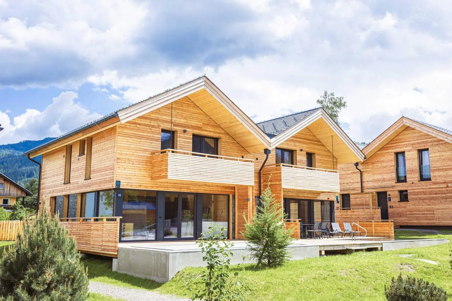 Zwei zeitgenössische Holzvillas nebeneinander mit weißen Balkonbrüstungen