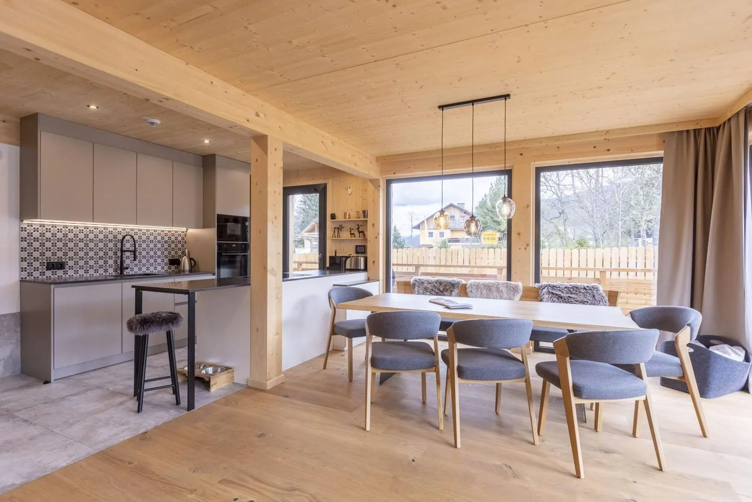 Offene Wohn-Essküche mit Holzdecke und großen Panoramafenstern