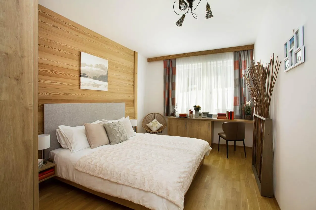 Großes Schlafzimmer mit Holzwand und gepolstertem Kopfteil