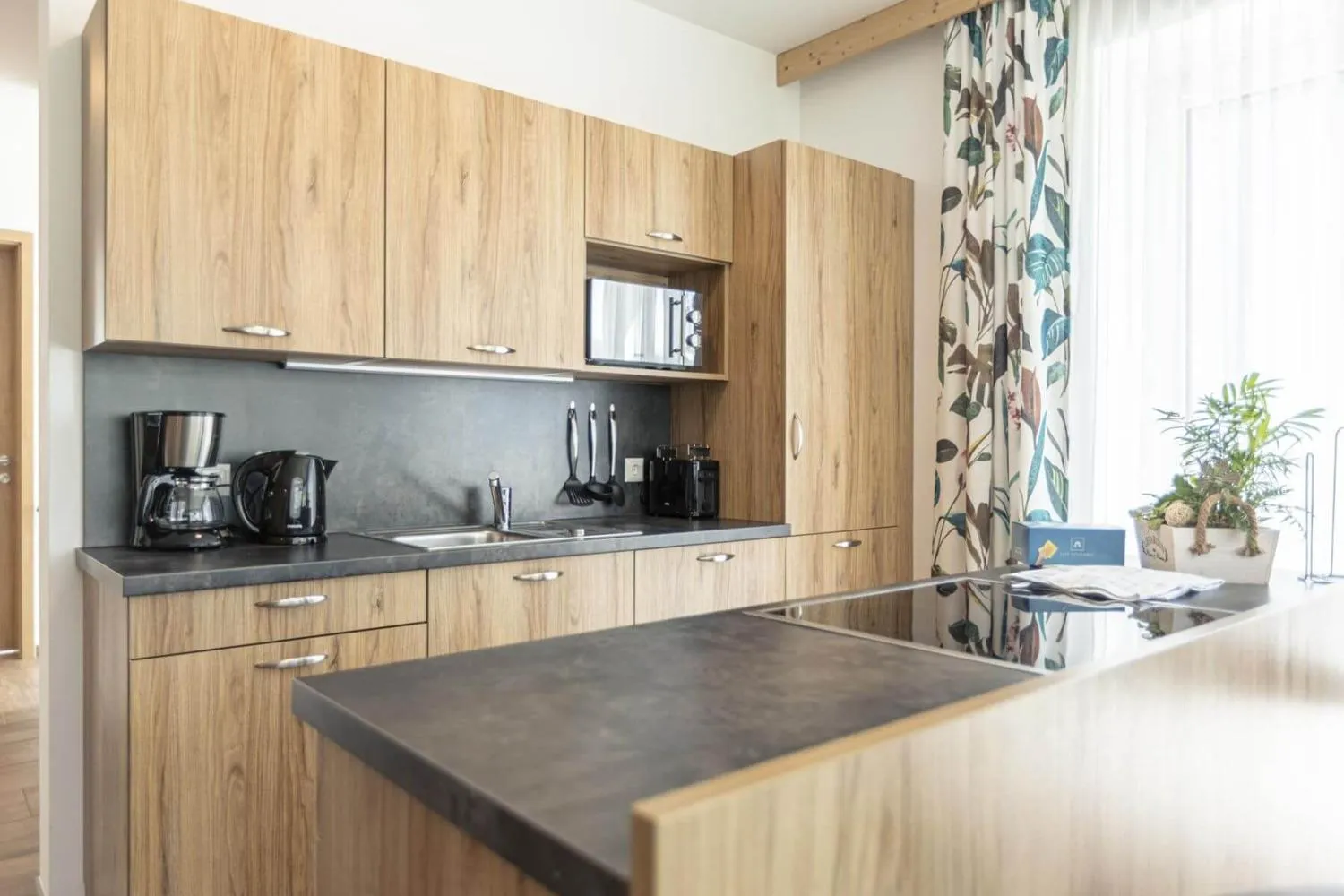 Holzküche mit schwarzer Arbeitsfläche und eingebauten Geräten