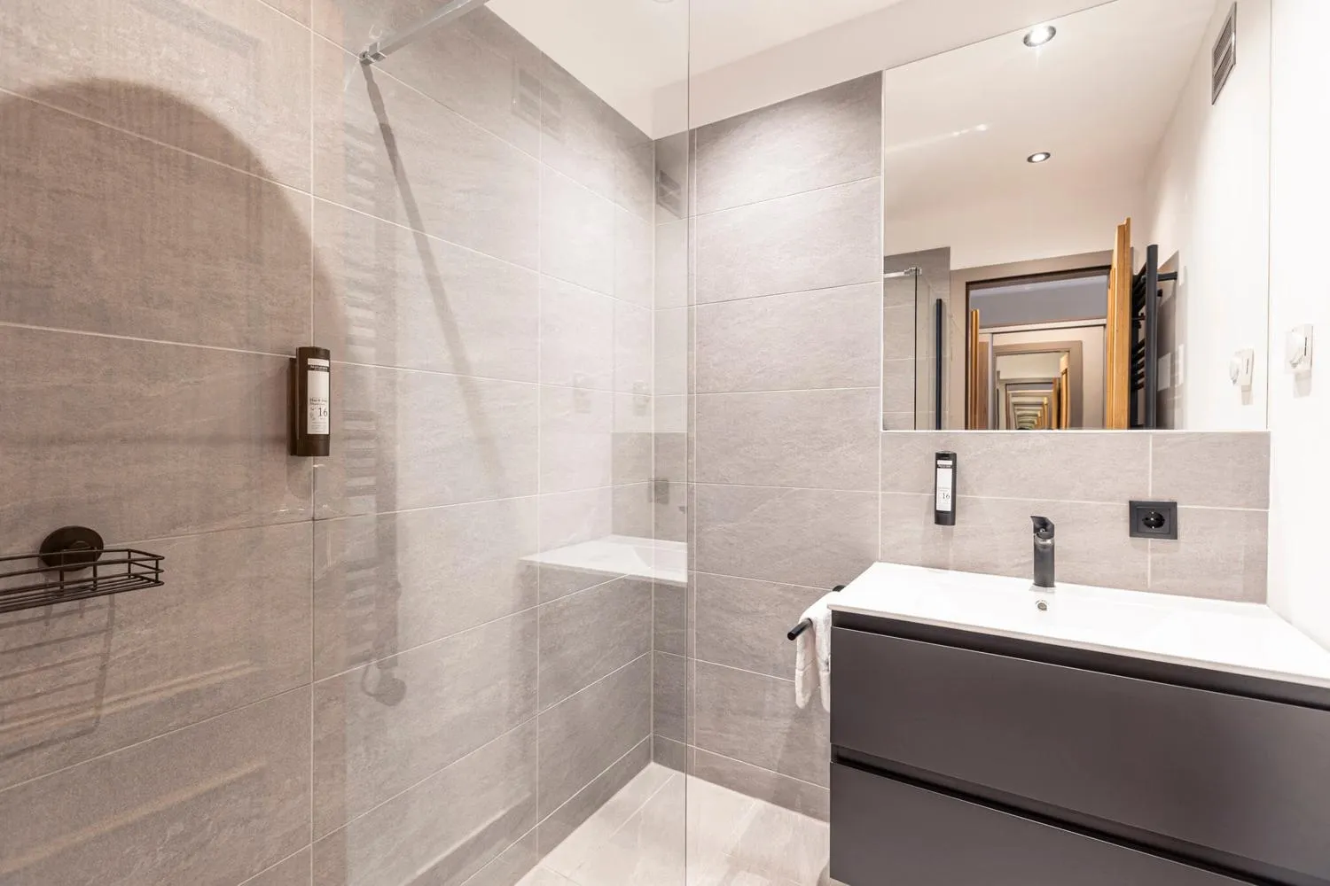 Badezimmer mit beige Fliesen, Glasdusche und großem Spiegel