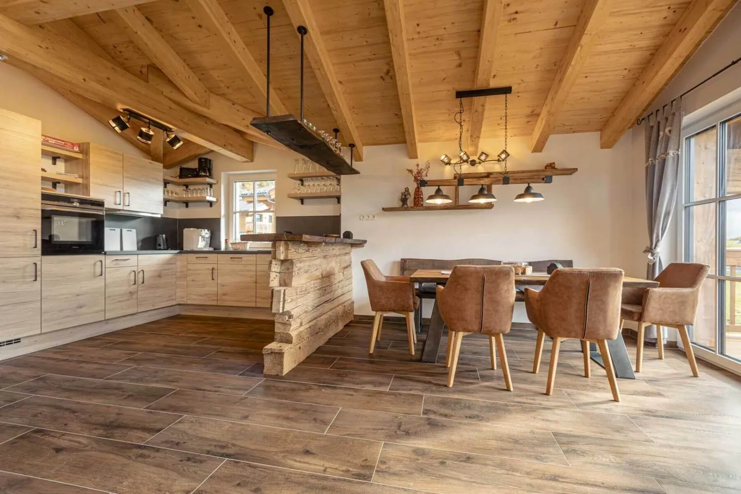 Offener Wohn-Ess-Küchenbereich mit großem Tisch und Holzbalkendecke